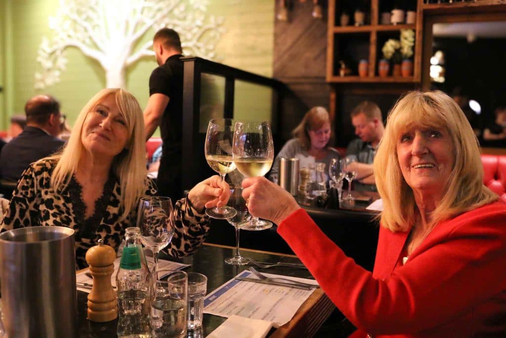Two friends raising their wine glasses at The Olive Tree