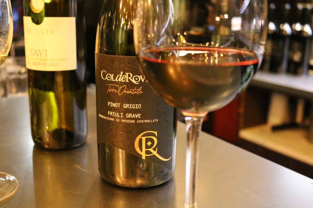 A bottle of white wine and a full glass on the bar